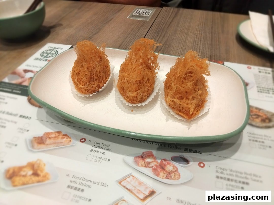 A plate of crispy fried dim sum on a table with a visible menu from Tim Ho Wan.