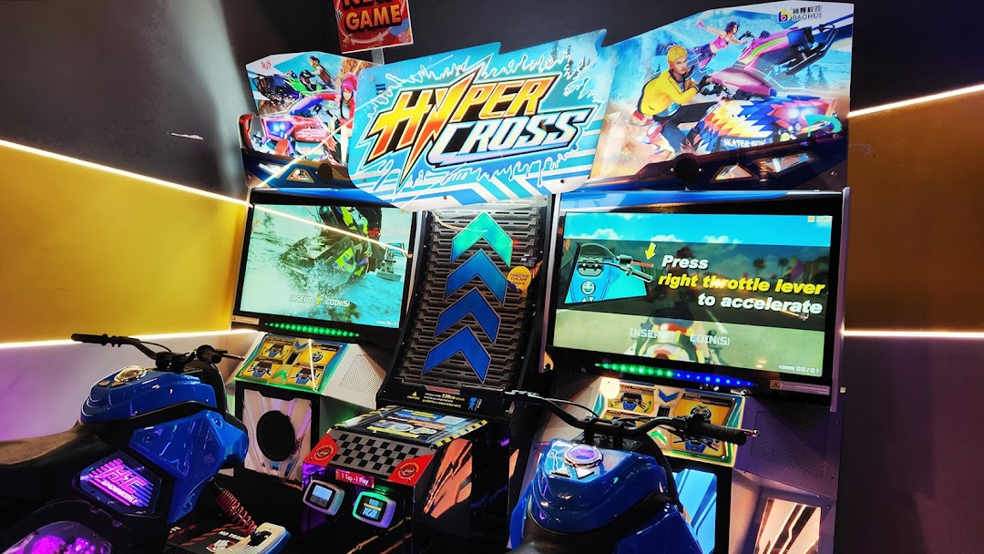 A vibrant arcade game featuring two motorcycle racing simulators with large screens.