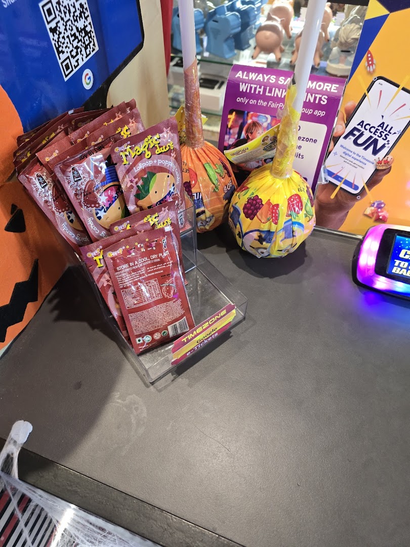 A counter display at Timezone featuring candies, lollipops, and promotional materials for their digital experience and e-tickets.