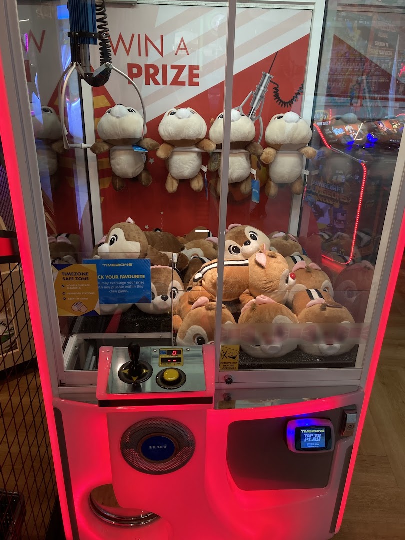 A brightly lit claw machine filled with plush toys, inviting players to win a prize.