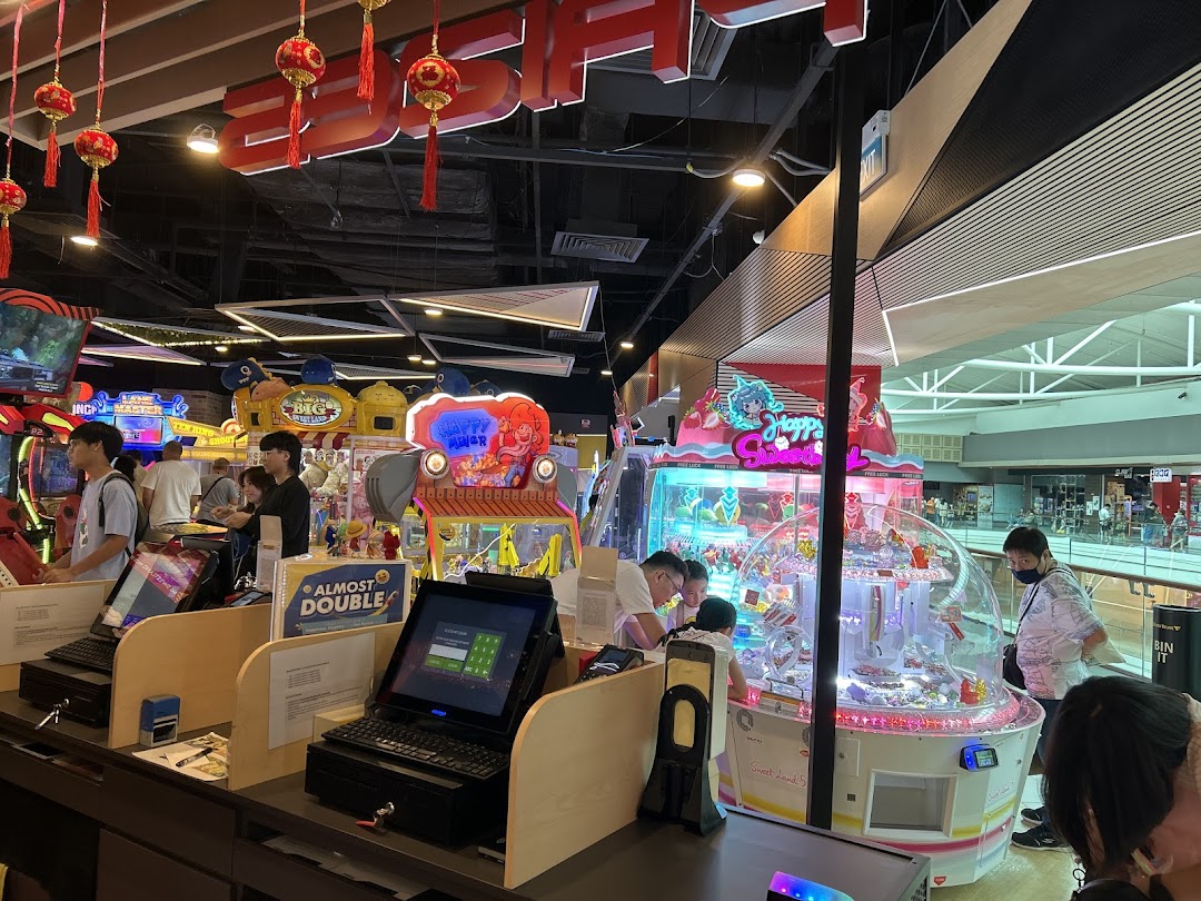 An vibrant arcade interior with various games, claw machines, and people enjoying the entertainment.