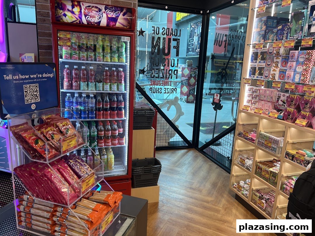 An arcade interior featuring a well-stocked drink fridge, a vibrant prize shop display, and a view of the entrance.