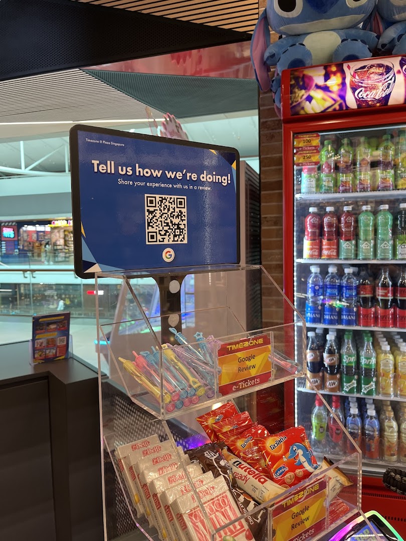 An interior shot of Timezone, featuring a customer feedback sign, small merchandise display, and beverage fridge.