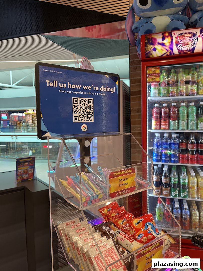 An interior shot of Timezone, featuring a customer feedback sign, small merchandise display, and beverage fridge.