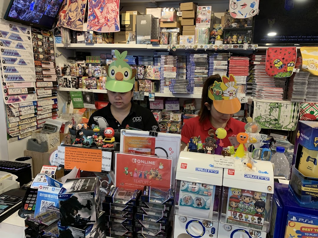 Two staff members wearing character visors behind a counter filled with video games, toys, and collectibles.
