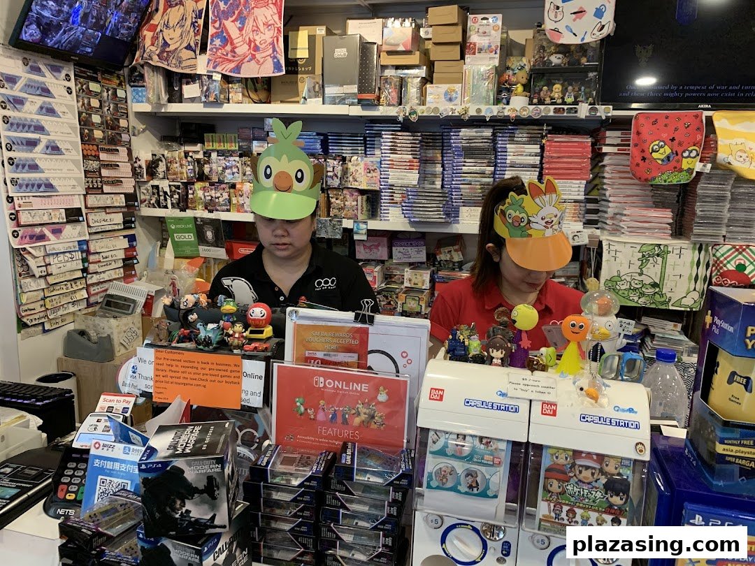 Two staff members wearing character visors behind a counter filled with video games, toys, and collectibles.