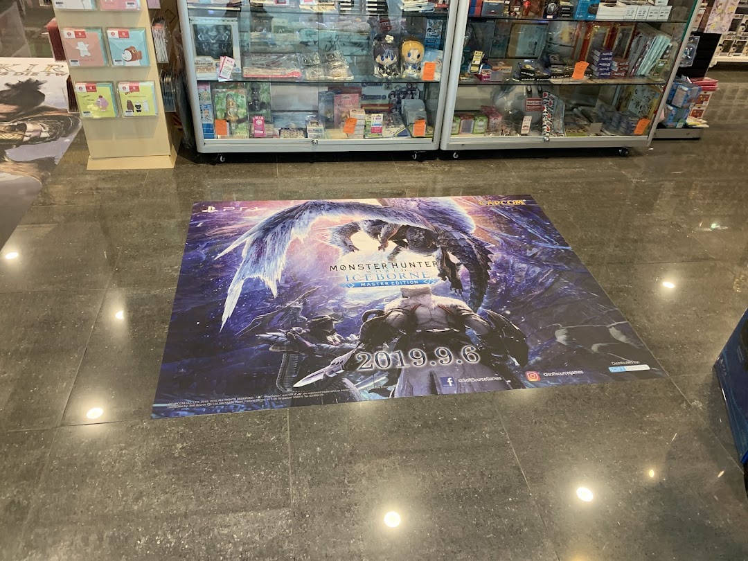 A large Monster Hunter Iceborne floor decal inside TOG - Toy Or Game Plaza Singapura, with display cases in the background.