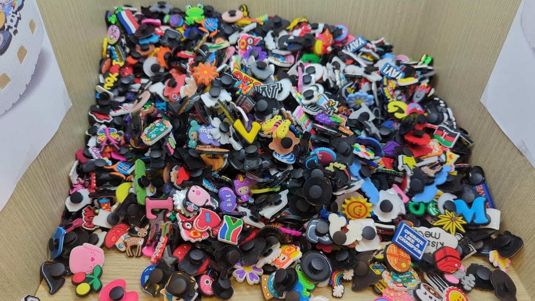 A close-up view of a large bin filled with colorful shoe charms and accessories.