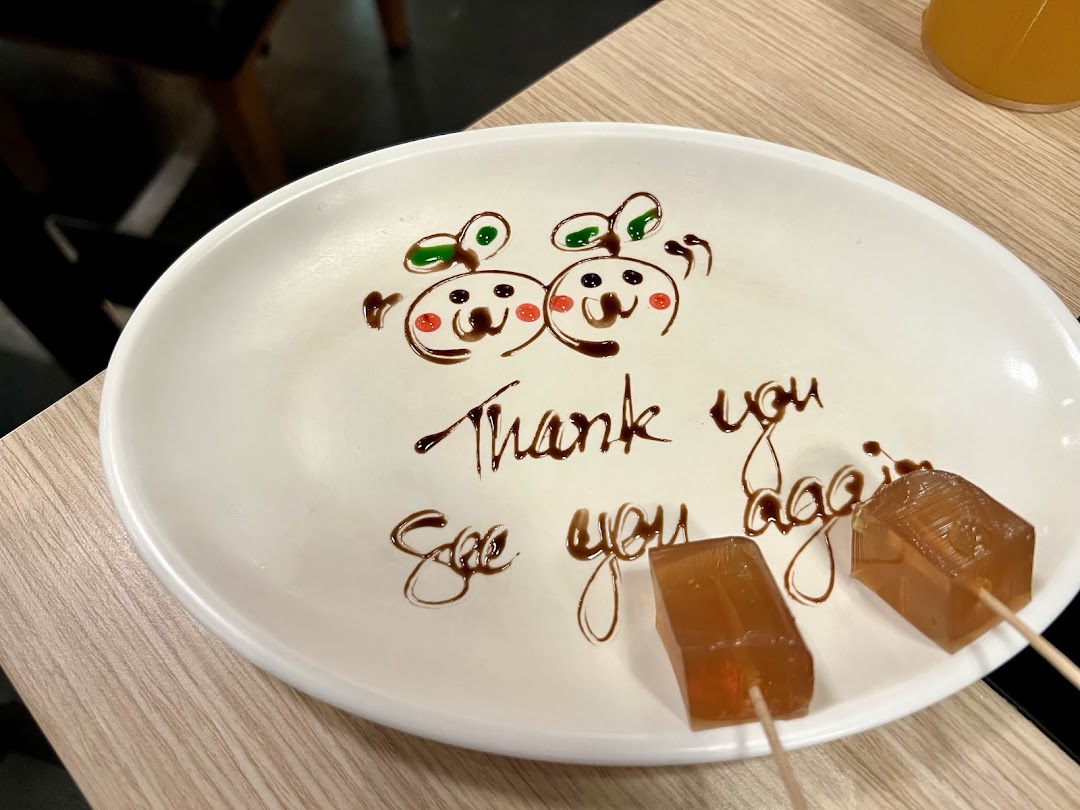 A white plate with a chocolate 'Thank you, See you again' message and two jelly cubes.