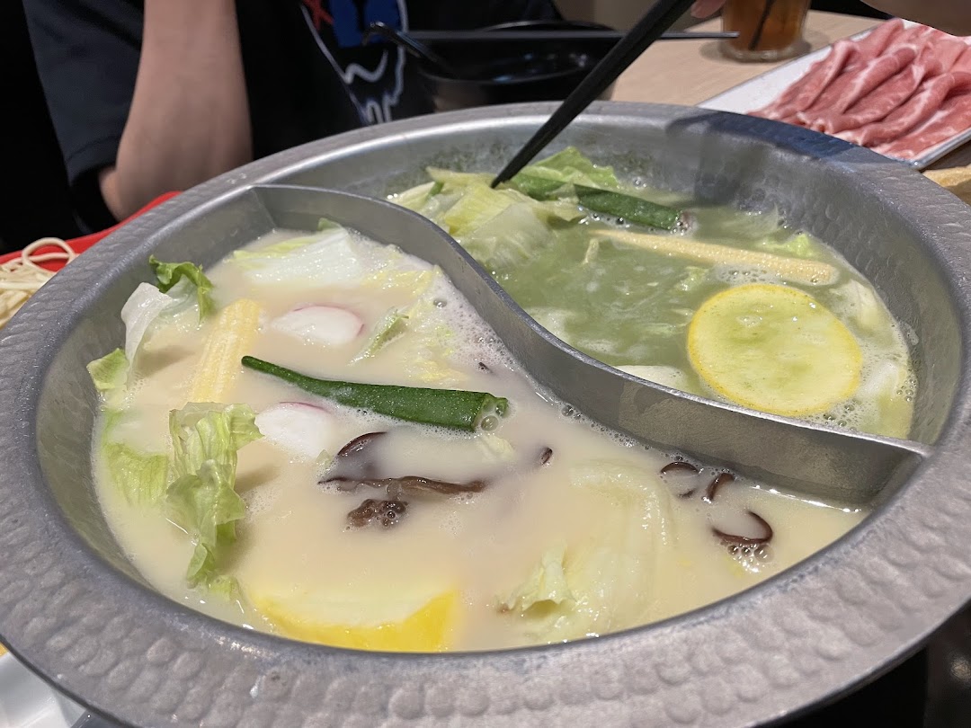 A bubbling hotpot with two distinct broths and fresh ingredients, ready for a delicious meal.