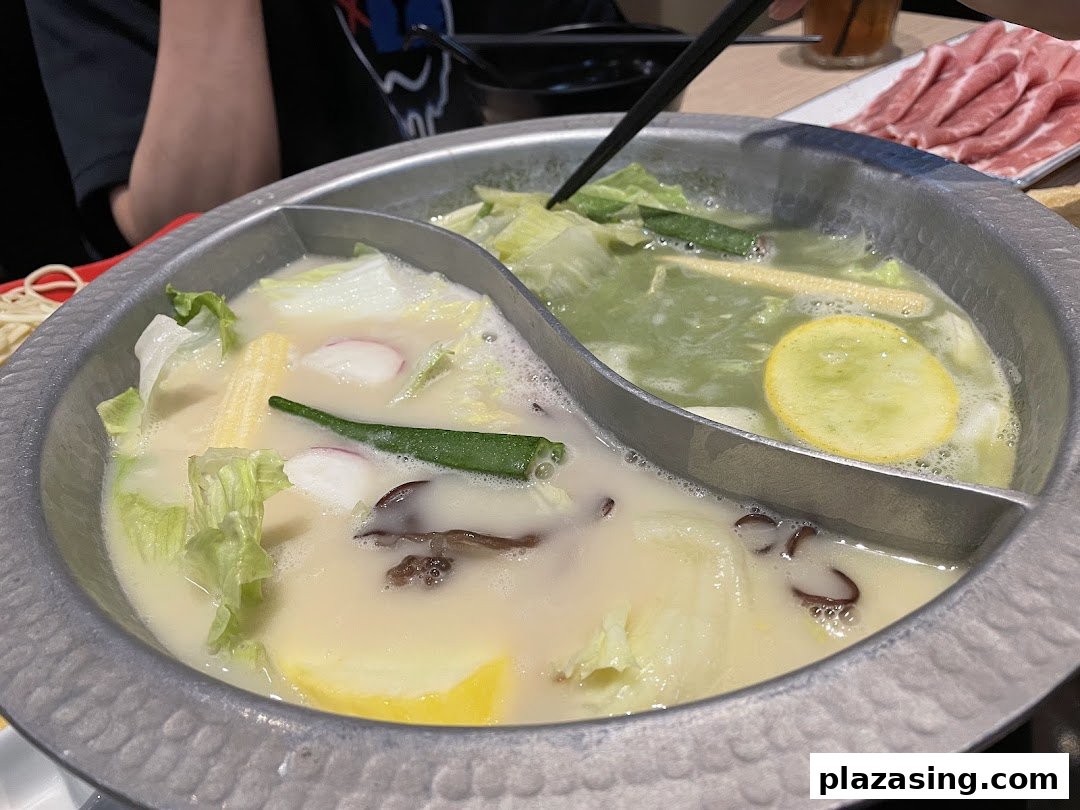 A bubbling hotpot with two distinct broths and fresh ingredients, ready for a delicious meal.