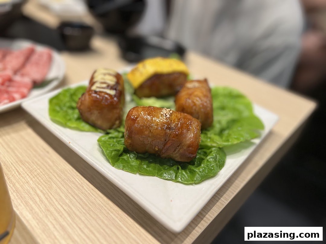 A plate of delicious-looking glazed chicken rolls served on fresh lettuce leaves.