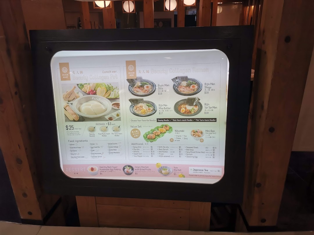 A brightly lit menu display showcasing Japanese hotpot, ramen, and side dishes with prices.