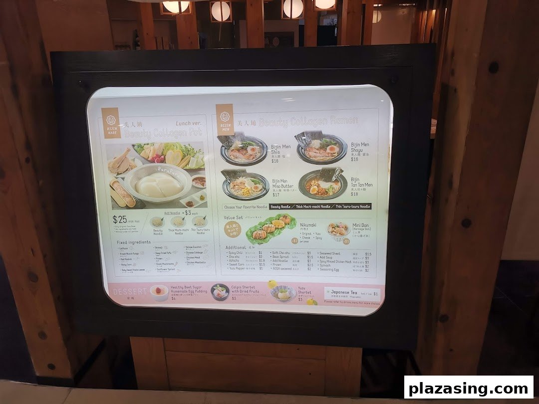 A brightly lit menu display showcasing Japanese hotpot, ramen, and side dishes with prices.