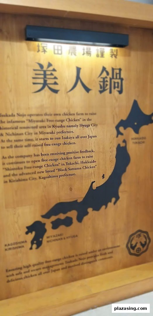 A wooden sign detailing Tsukada Nojo's commitment to sourcing premium free-range chicken from various Japanese prefectures.