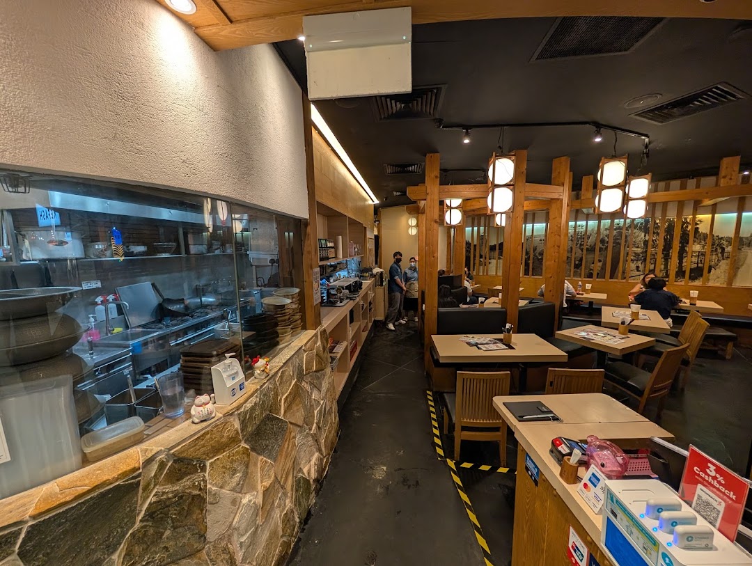 An interior view of Tsukada Nojo, showcasing the open kitchen and a cozy dining area with wooden decor.