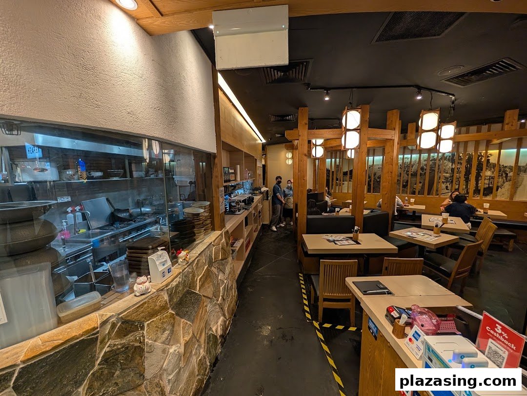 An interior view of Tsukada Nojo, showcasing the open kitchen and a cozy dining area with wooden decor.