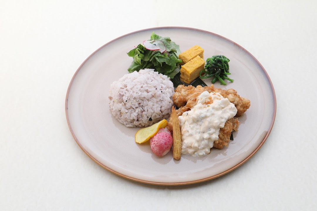 A beautifully plated Japanese set meal featuring fried chicken with tartar sauce, rice, salad, and sides.