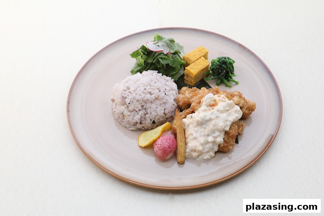 A beautifully plated Japanese set meal featuring fried chicken with tartar sauce, rice, salad, and sides.