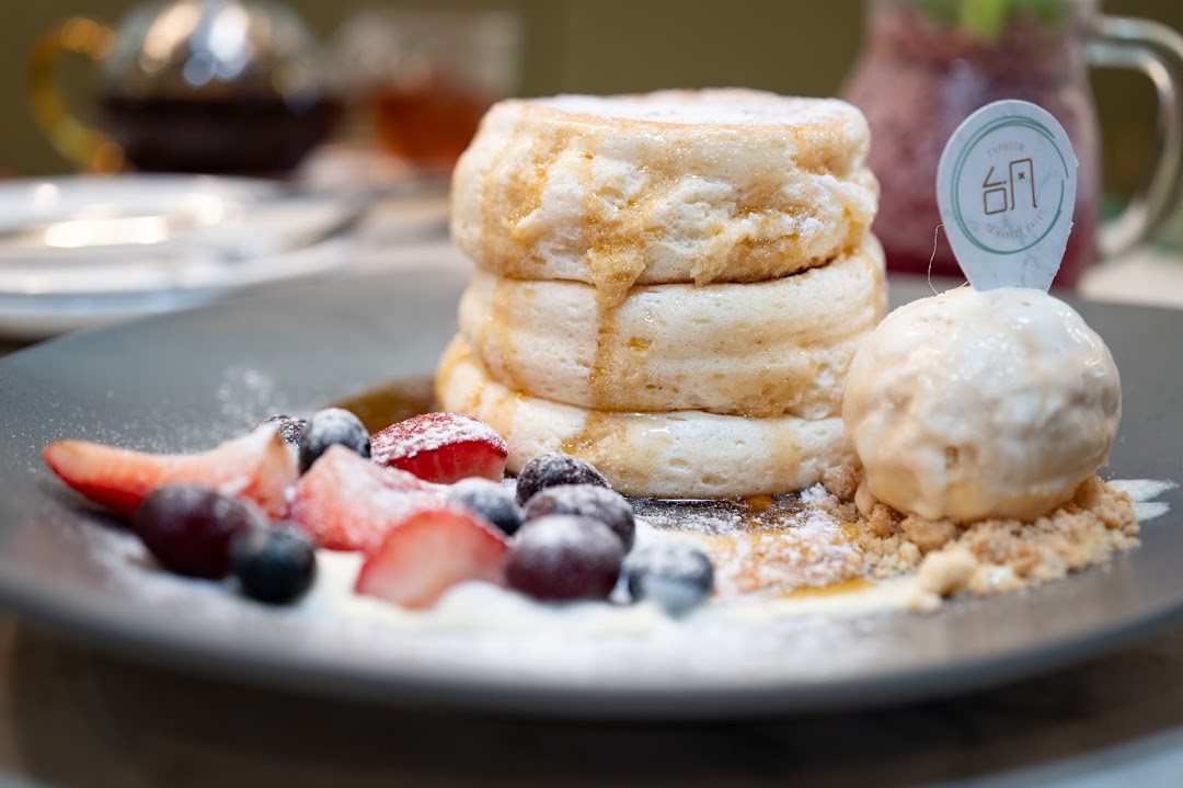Fluffy soufflé pancakes with berries, ice cream, and syrup on a dark plate.