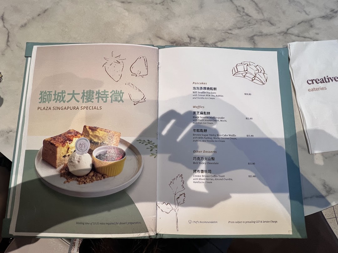 An open menu displaying 'Plaza Singapura Specials' desserts, including pancakes, waffles, and other sweet treats.