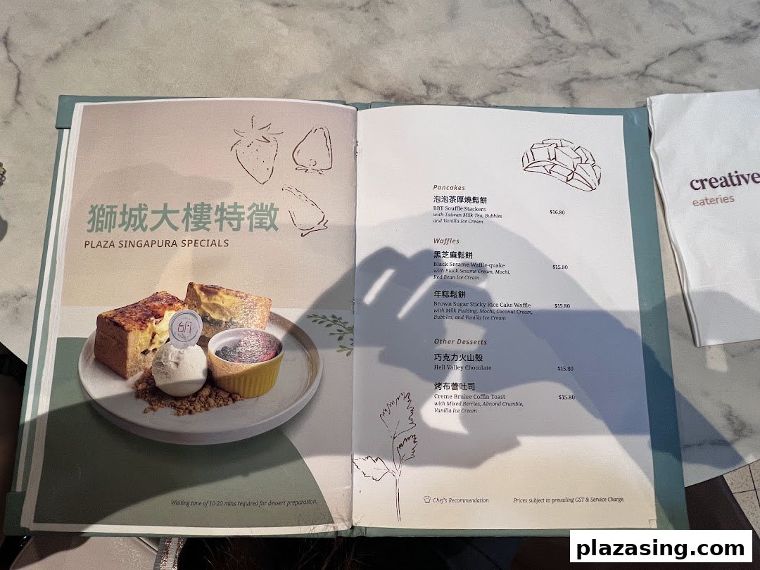 An open menu displaying 'Plaza Singapura Specials' desserts, including pancakes, waffles, and other sweet treats.