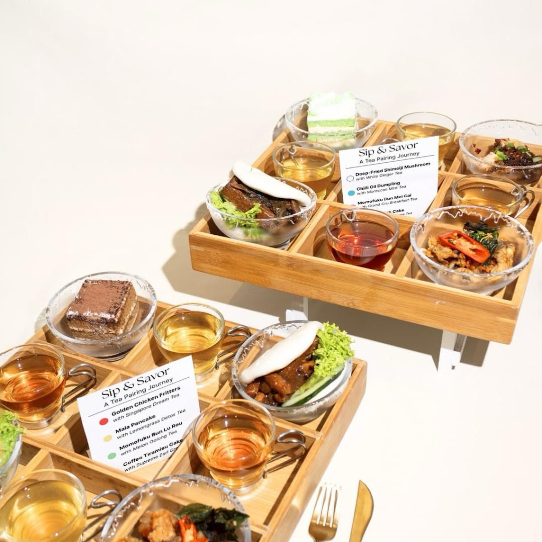 Two wooden trays showcase a 'Sip & Savor' tea pairing journey with various small dishes and teas.