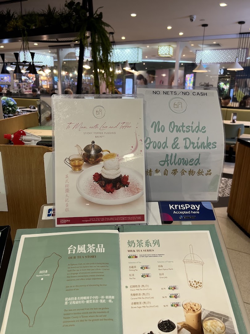 A close-up of menu displays and promotional materials inside Typhoon Cafe, featuring desserts and milk teas.