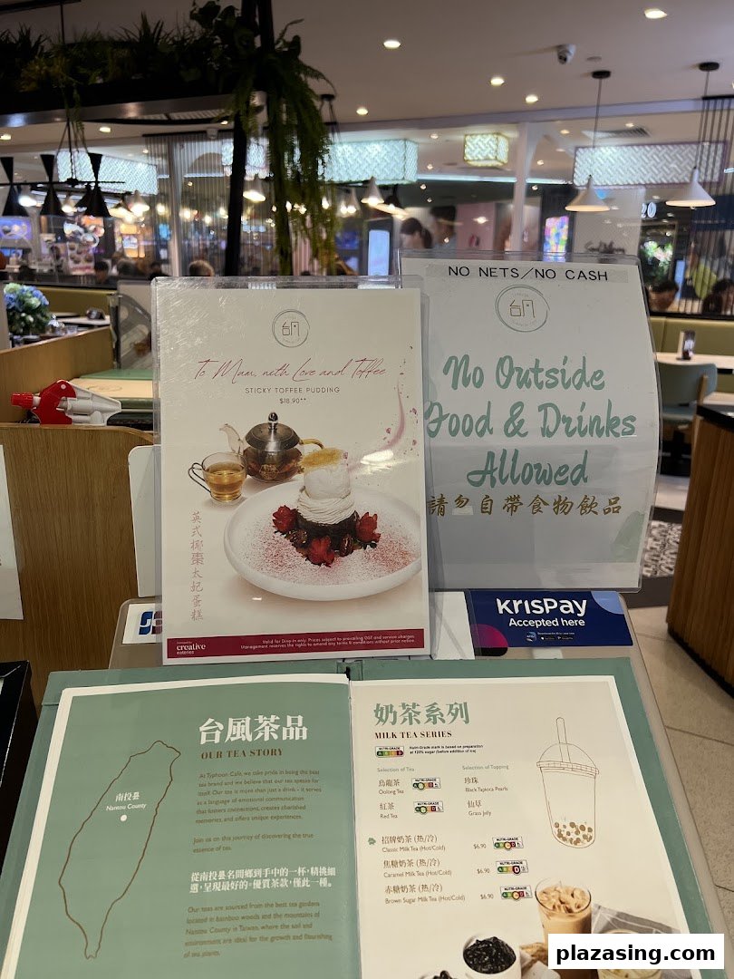 A close-up of menu displays and promotional materials inside Typhoon Cafe, featuring desserts and milk teas.