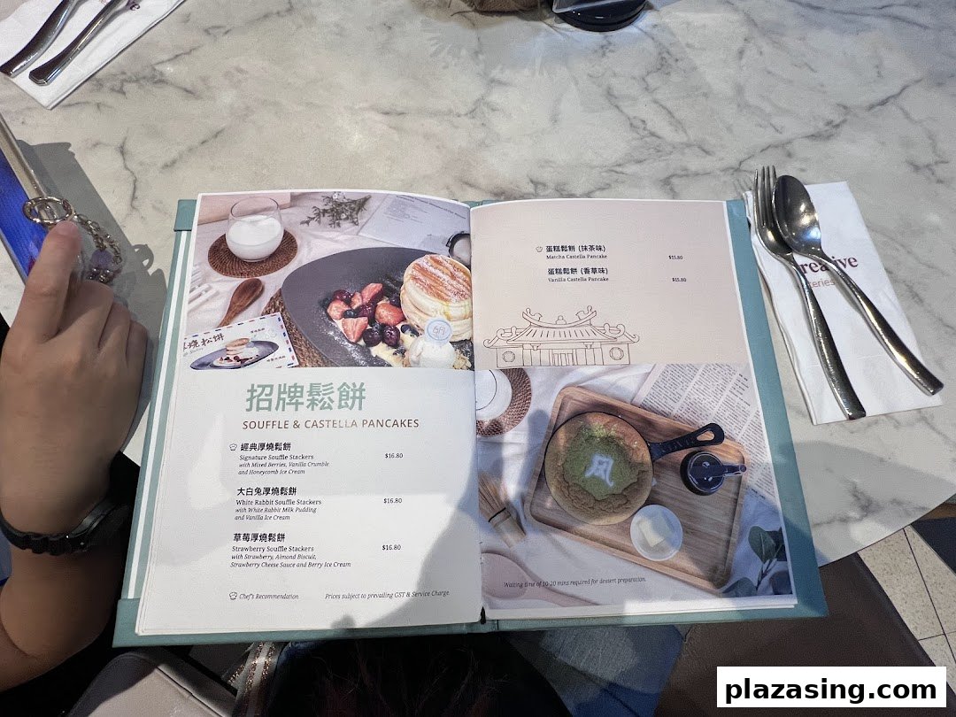 An open menu displaying various souffle and castella pancake options with prices at Typhoon Cafe.