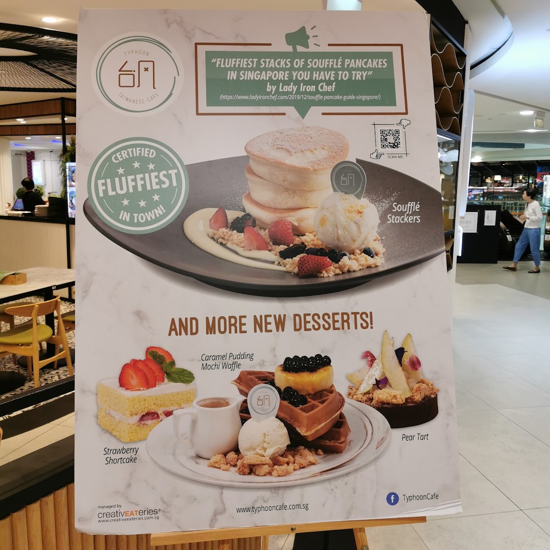 A promotional standee for Typhoon Cafe showcasing their signature soufflé pancakes and new desserts.