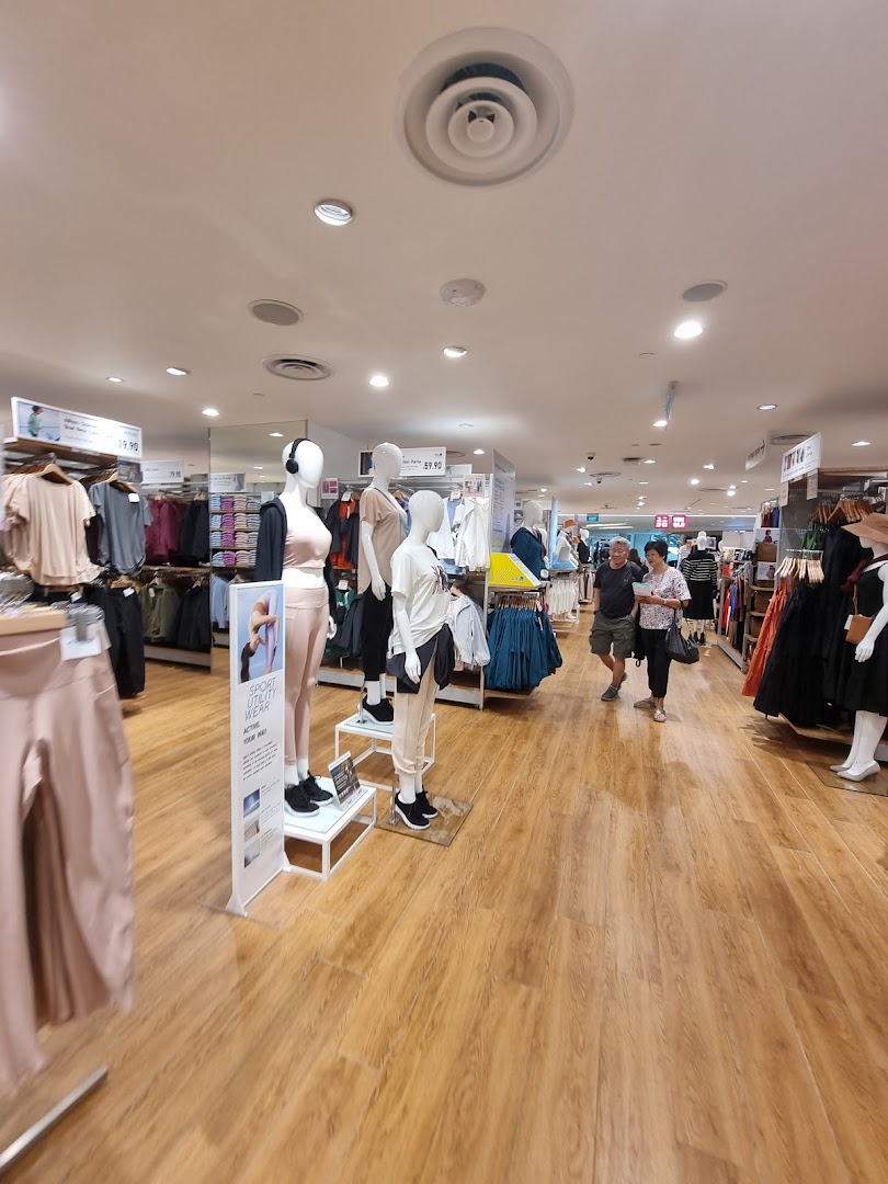 Inside UNIQLO, showcasing a wide range of apparel on mannequins and racks, with customers browsing.
