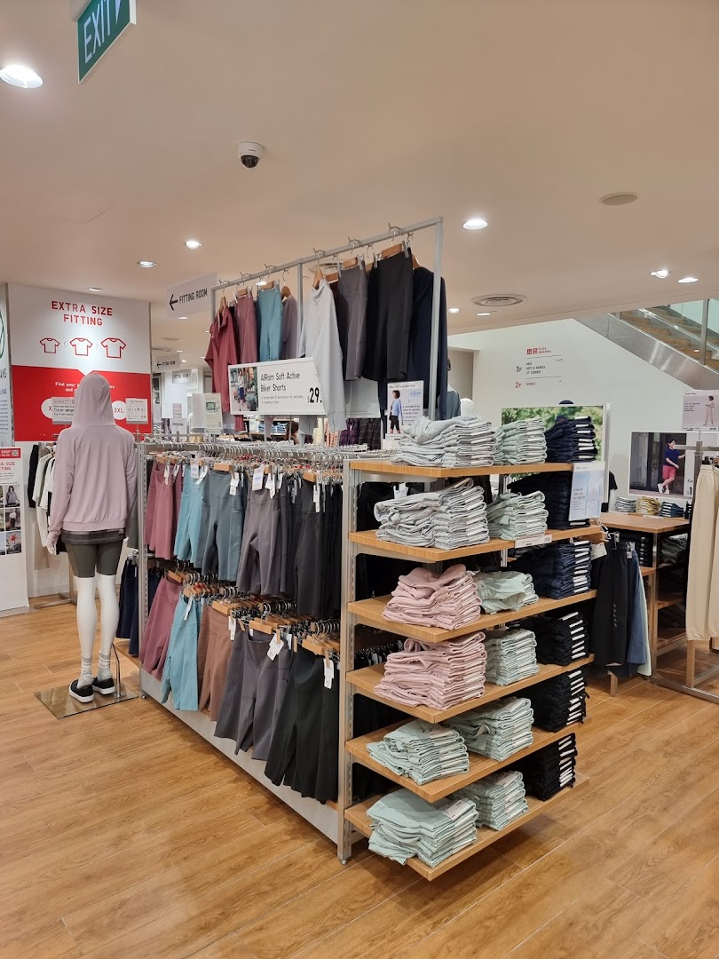 Interior view of UNIQLO, showcasing activewear displays, folded apparel, and a mannequin in a spacious setting.