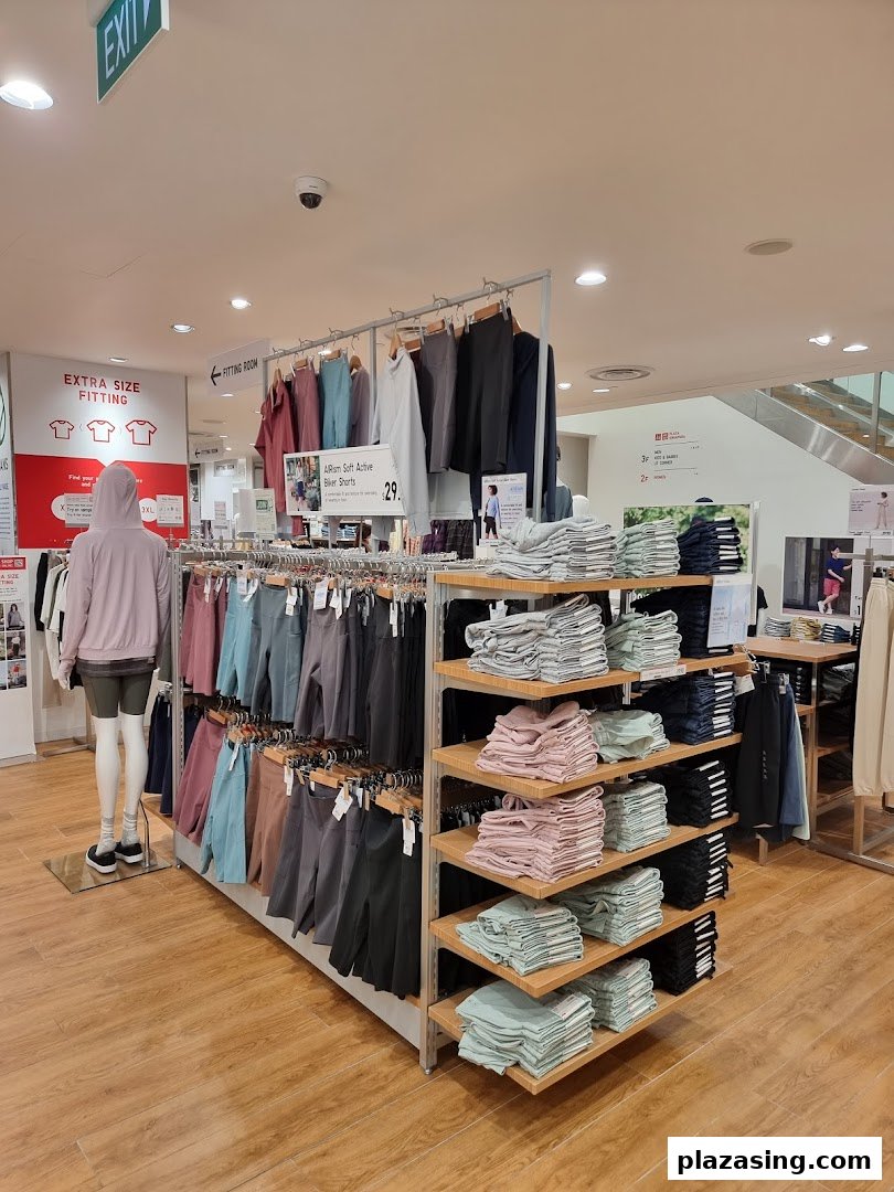 Interior view of UNIQLO, showcasing activewear displays, folded apparel, and a mannequin in a spacious setting.