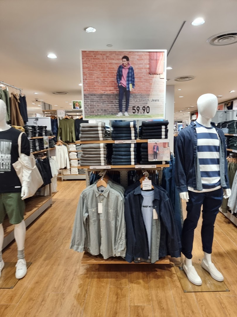 An interior view of UNIQLO showcasing casual wear on mannequins and neatly folded apparel displays.