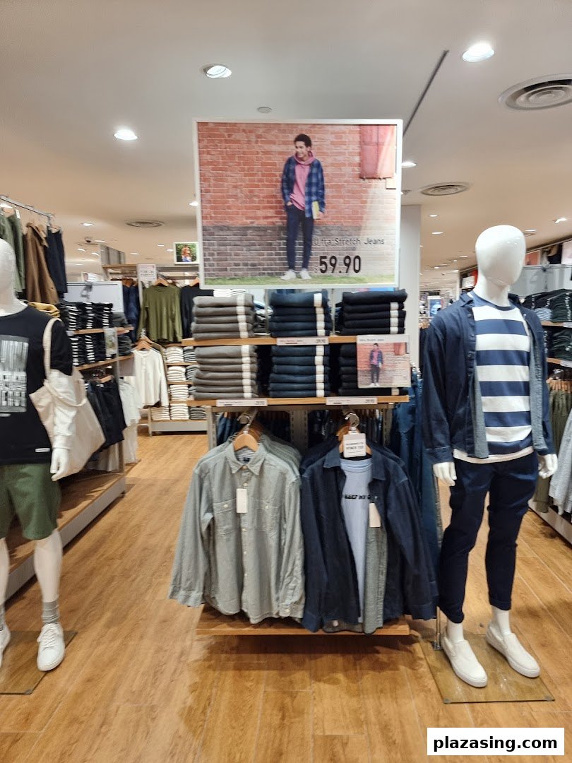 An interior view of UNIQLO showcasing casual wear on mannequins and neatly folded apparel displays.