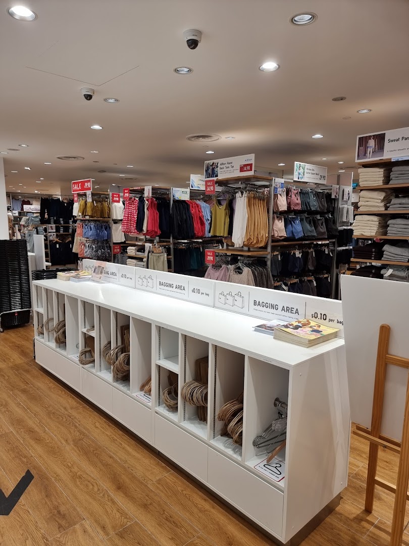 Interior view of UNIQLO, showcasing clothing displays, sale items, and a self-service bagging area.