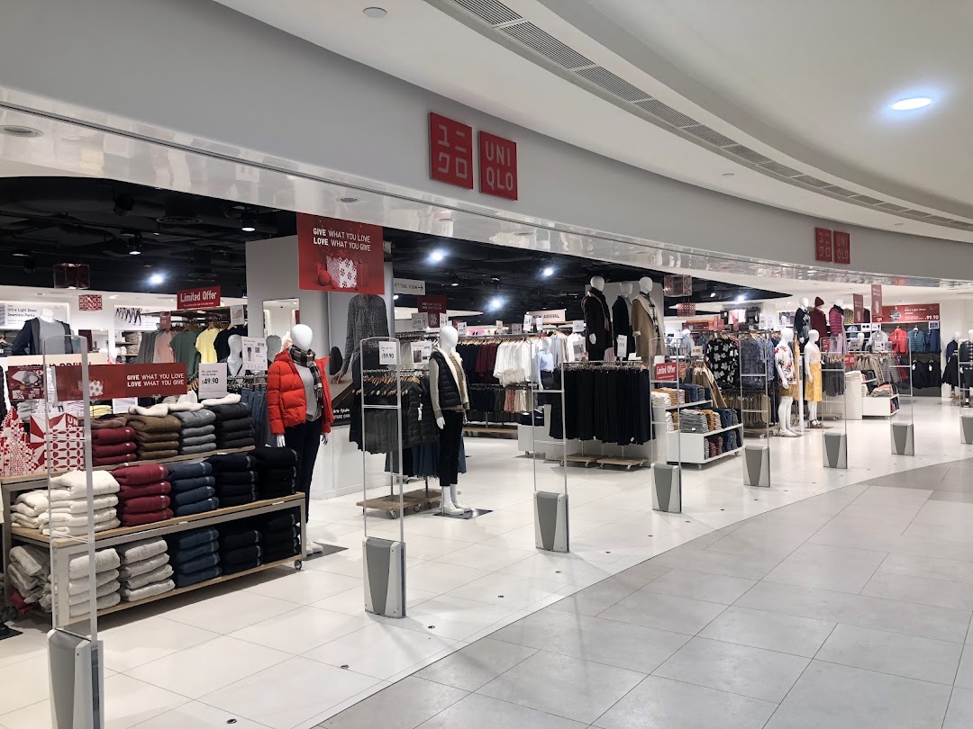 An interior view of UNIQLO, showcasing various clothing displays, mannequins, and promotional signage.