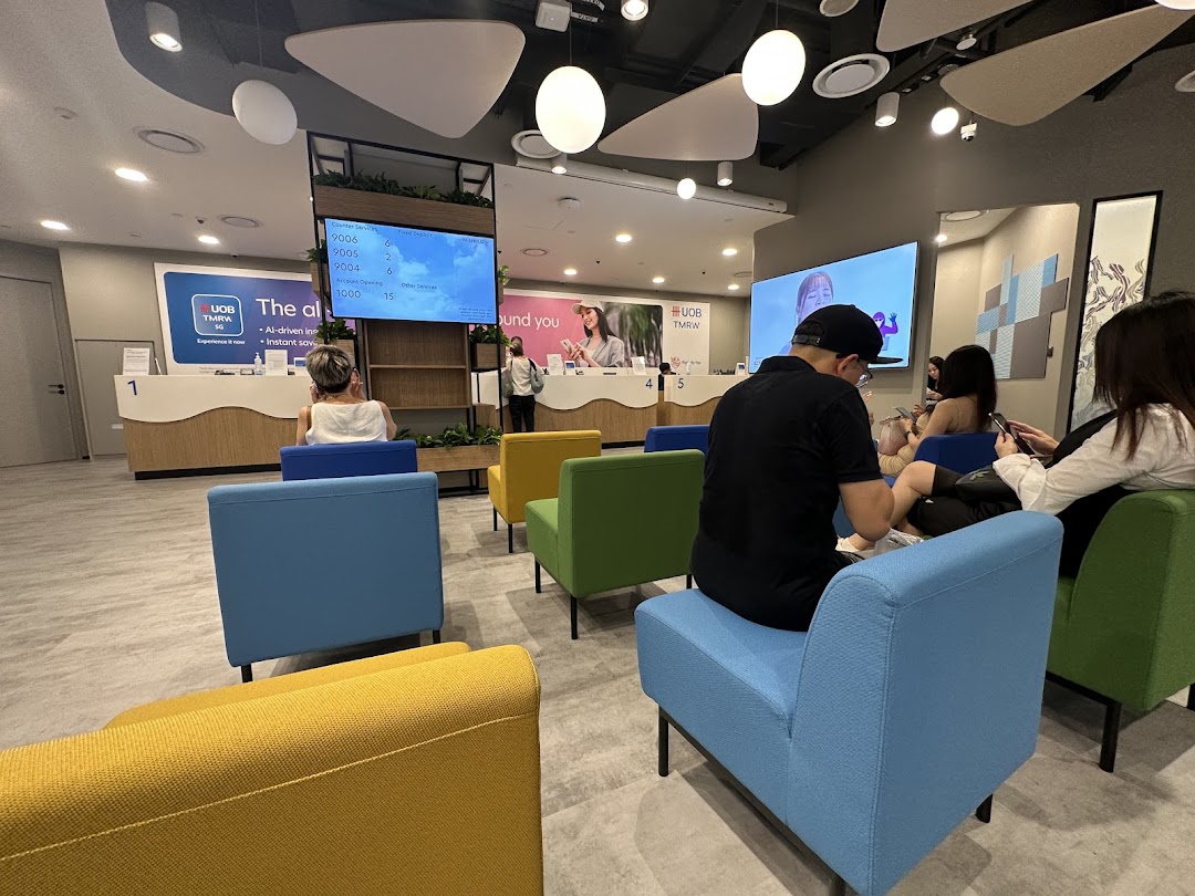 Customers wait in a modern UOB bank branch with colorful seating and digital displays.