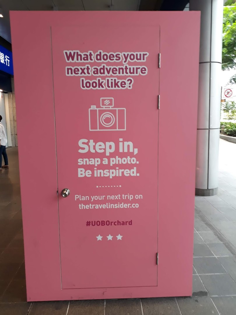 A pink interactive display inviting visitors to imagine their next adventure and snap a photo.