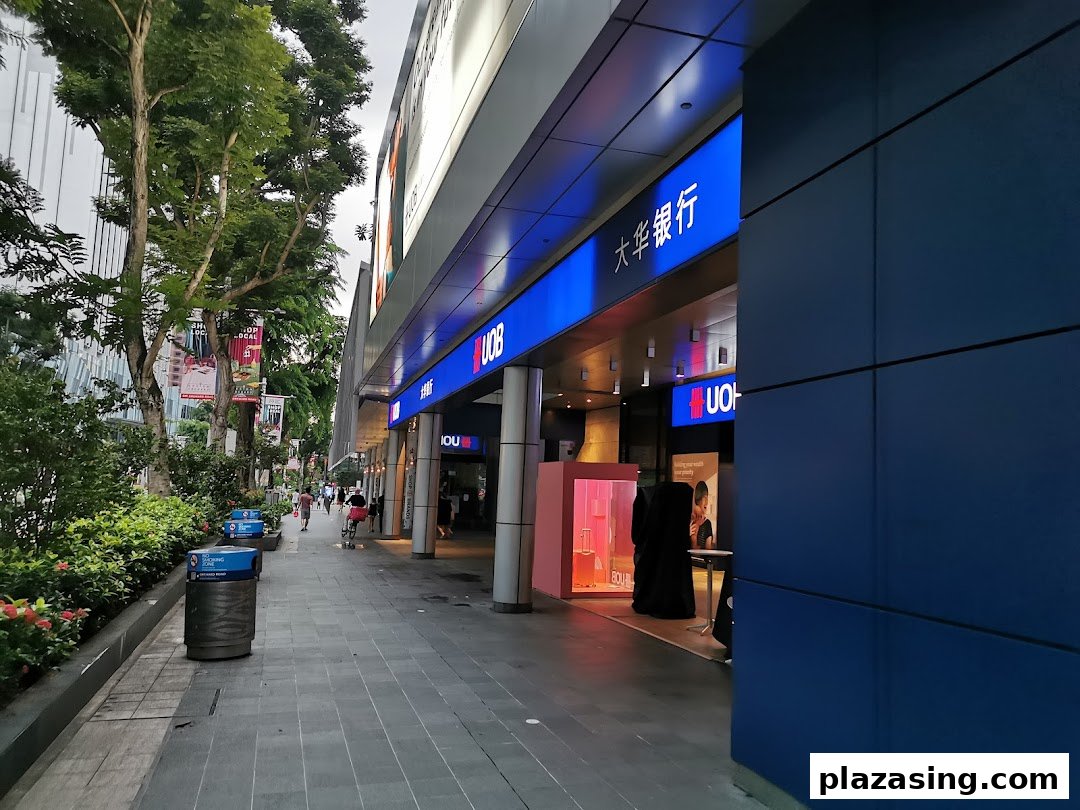 Exterior view of the UOB bank branch on a bustling street with pedestrians and lush greenery.