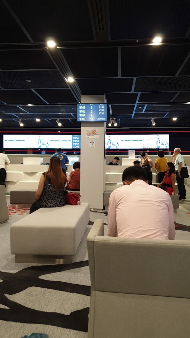 Customers waiting in a modern UOB bank branch with digital queue displays and service counters.