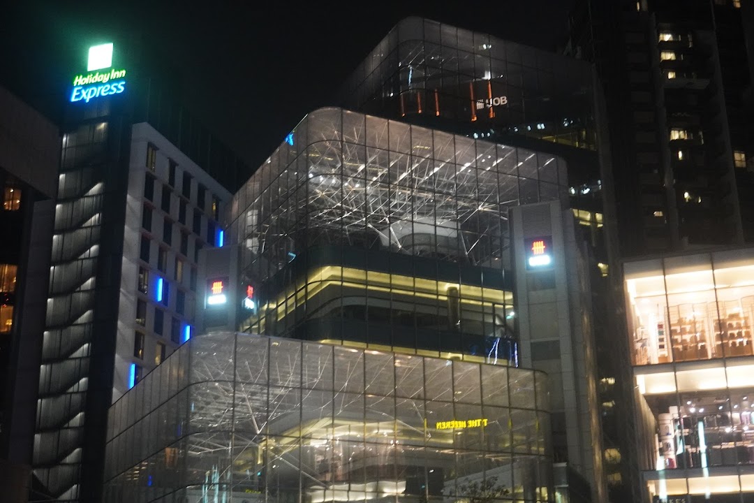 Night view of a modern building featuring illuminated signs for UOB and Holiday Inn Express.