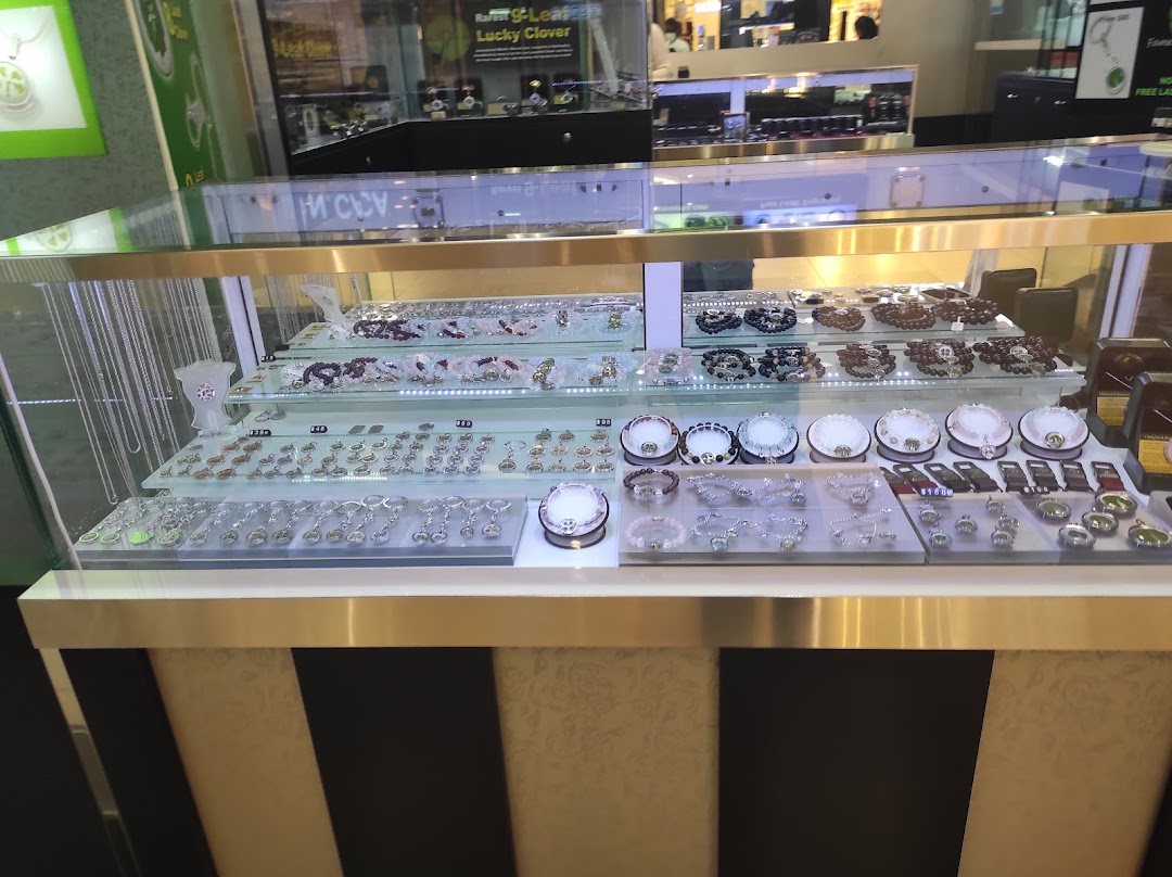A brightly lit display case showcasing a wide array of necklaces, bracelets, and charms.