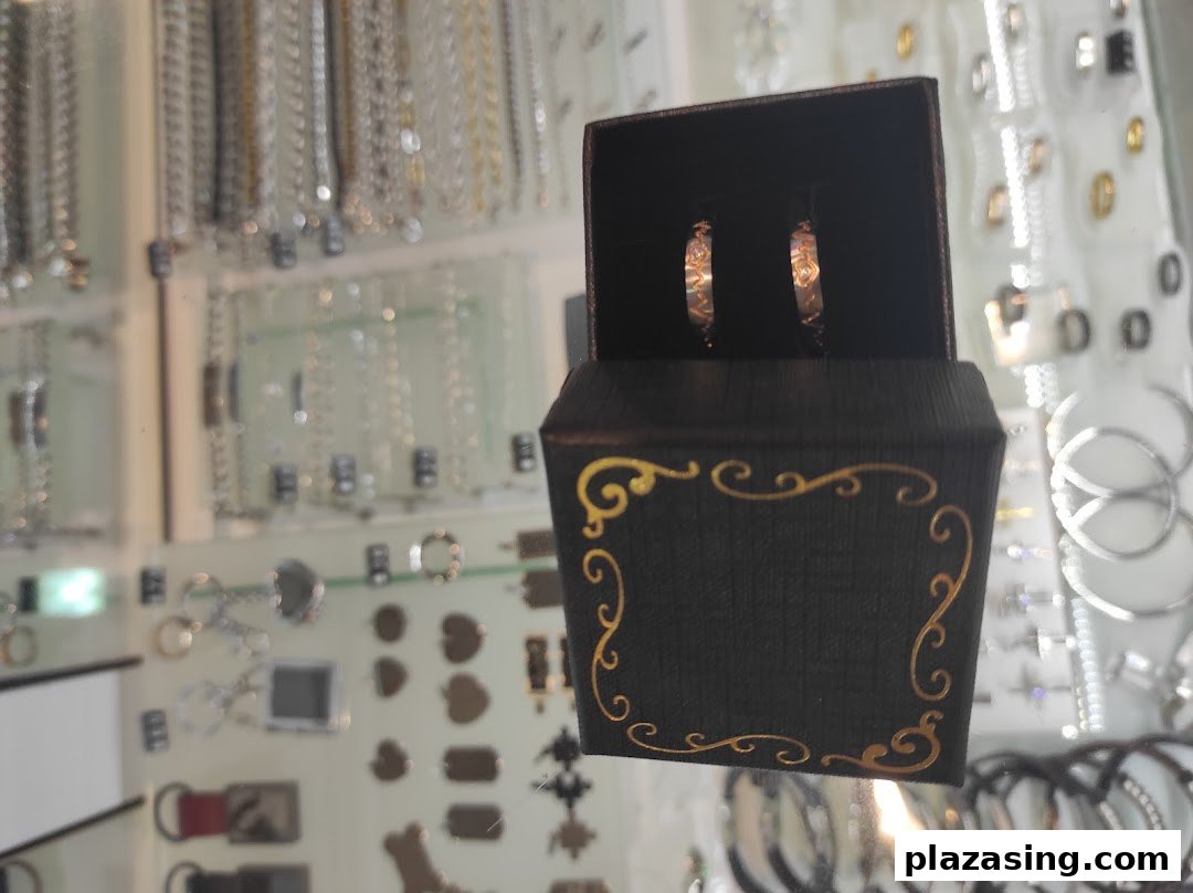 A pair of elegant earrings displayed in a decorative box, surrounded by various jewelry items.