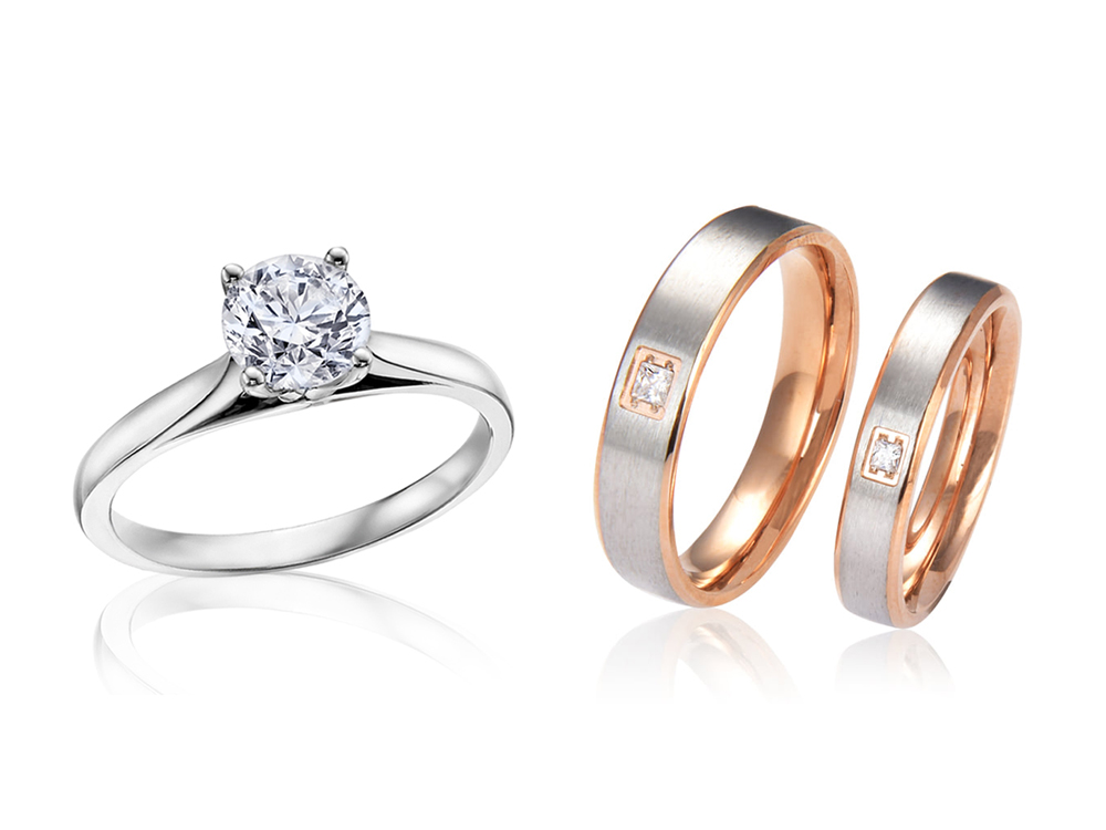 A close-up of a diamond solitaire engagement ring and a pair of two-tone wedding bands.