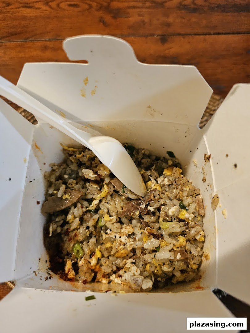 A close-up of delicious fried rice with meat and egg in a white takeaway box from WOK HEY.