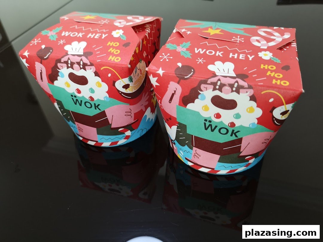 Two festive-themed WOK HEY takeaway boxes featuring a Santa-like chef design.