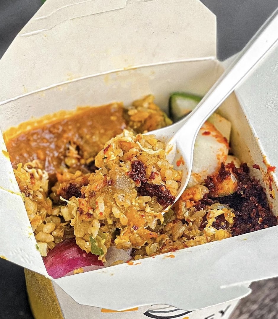 A close-up of a flavorful stir-fried noodle or rice dish in a Wok Hey takeaway box.