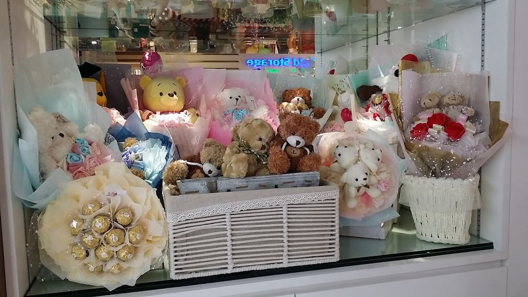 A display of various gift bouquets featuring plush toys, artificial flowers, and chocolates.